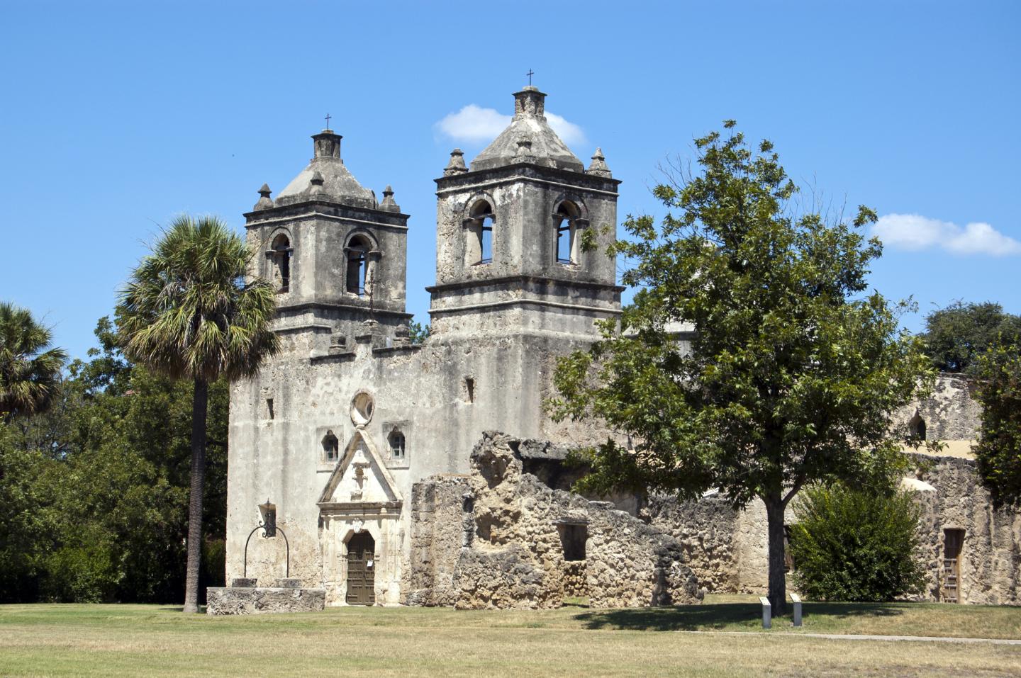 Historic San Antonio mission with twin bell towers under a clear blue sky.
