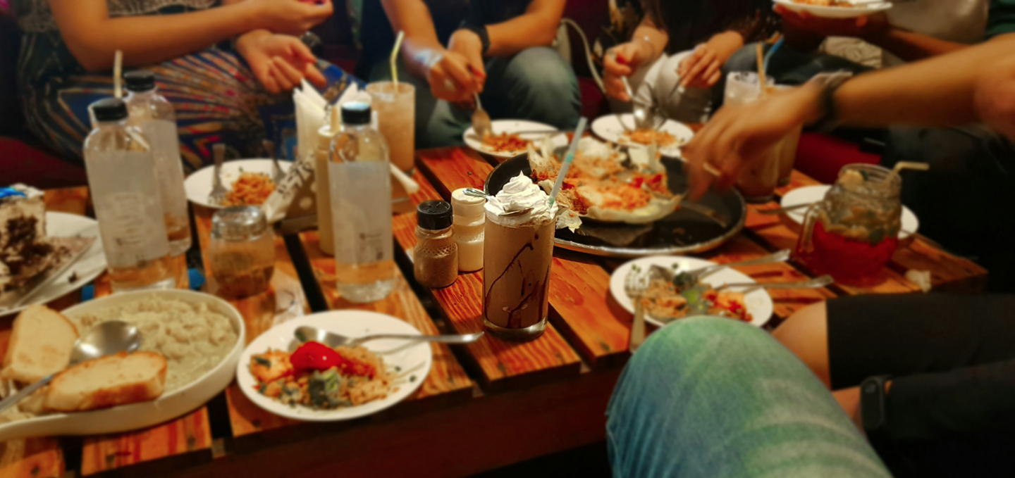 People dining at a table with plates of food and drinks.