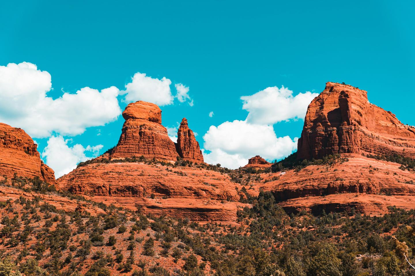 Sedona red rock formations under a bright blue sky with white clouds.