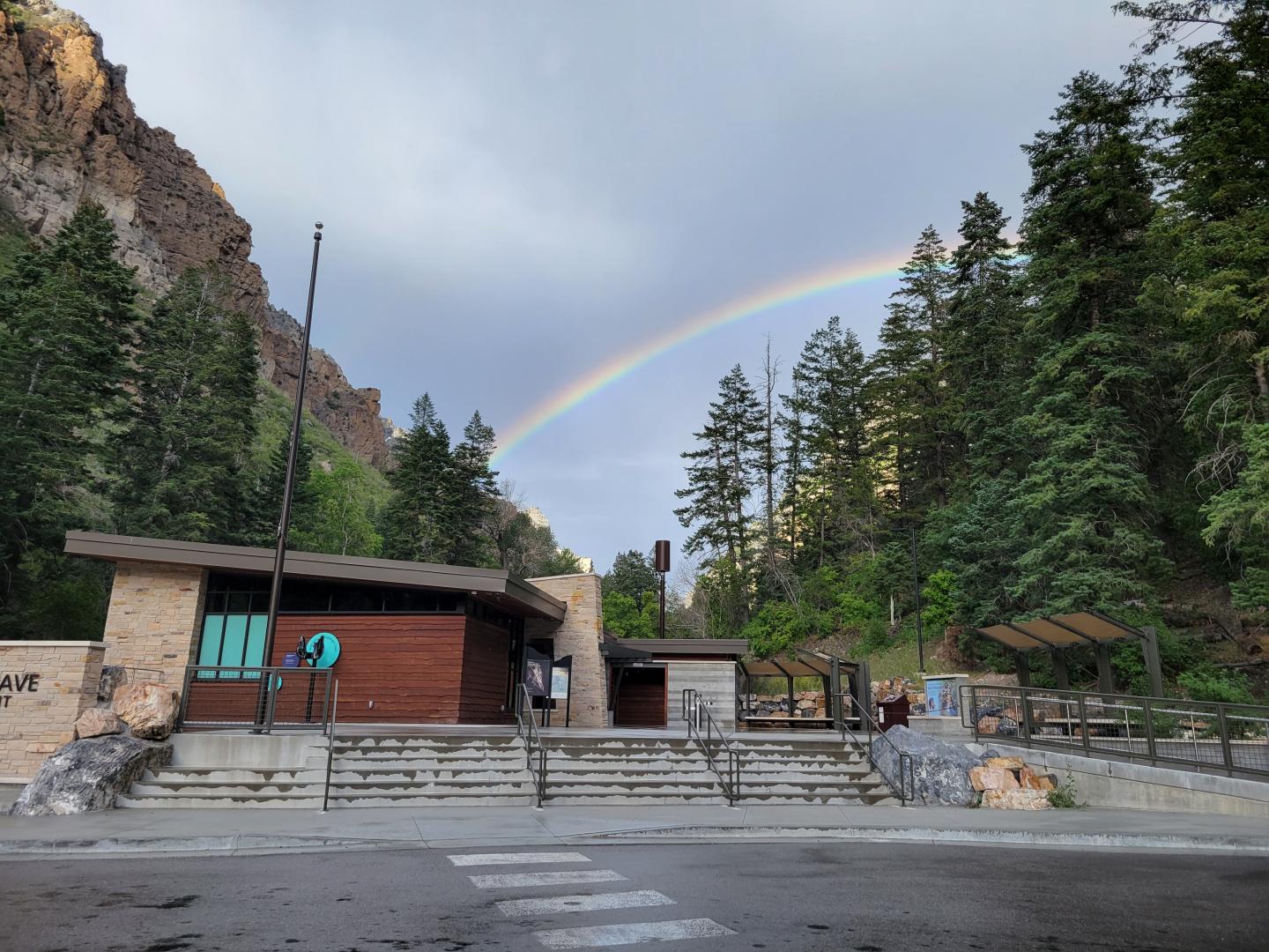 Visitor center in forested area with rainbow arcing over the sky.