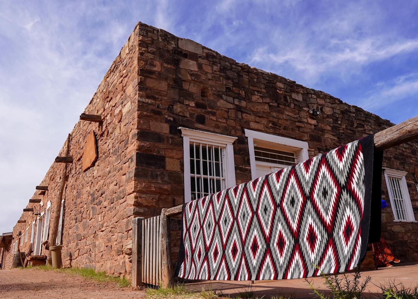 Hubbell trading post building with a colorful rug hanging on a railing.