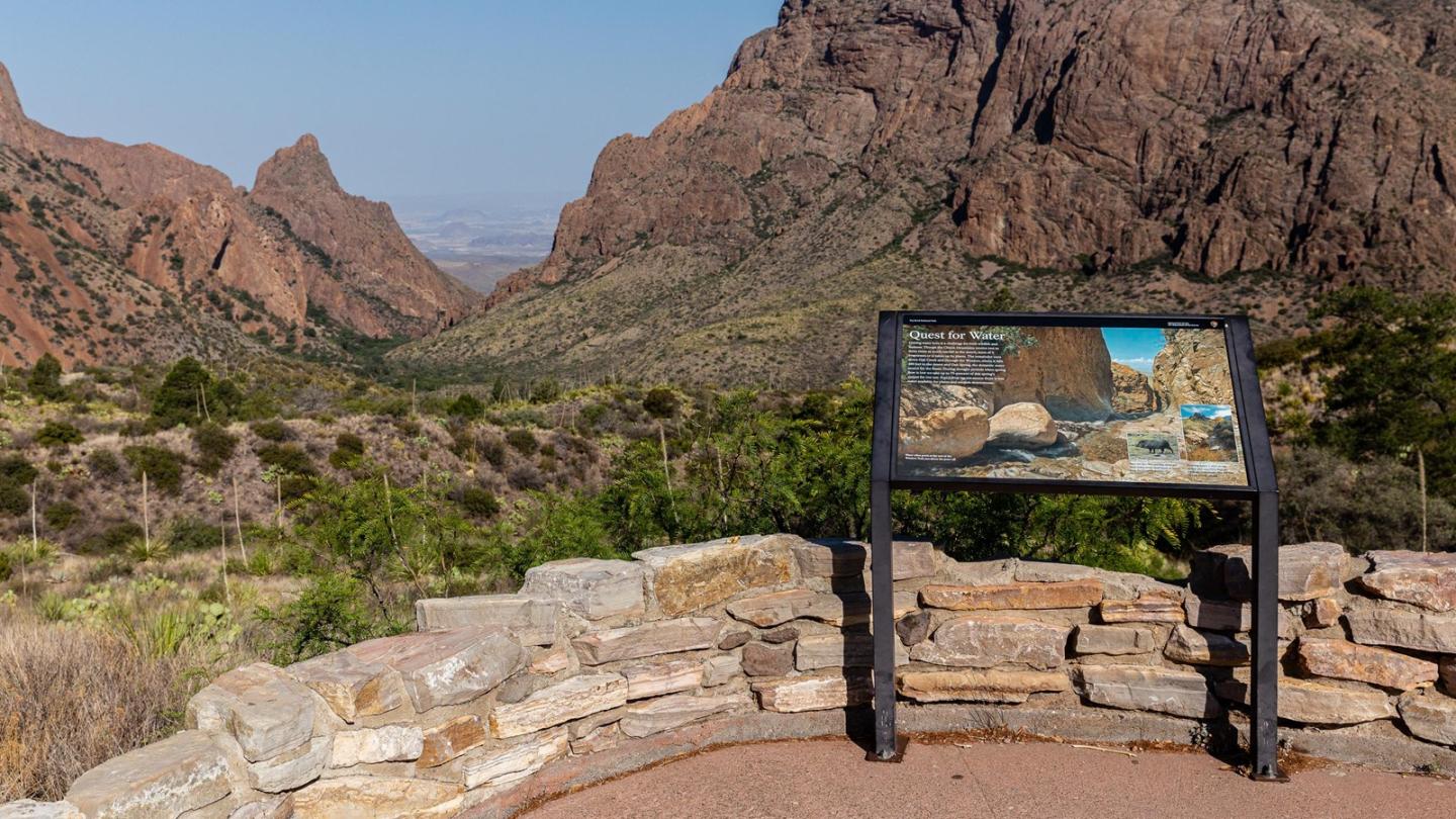 Stone overlook with a scenic mountain view and an informational sign.
