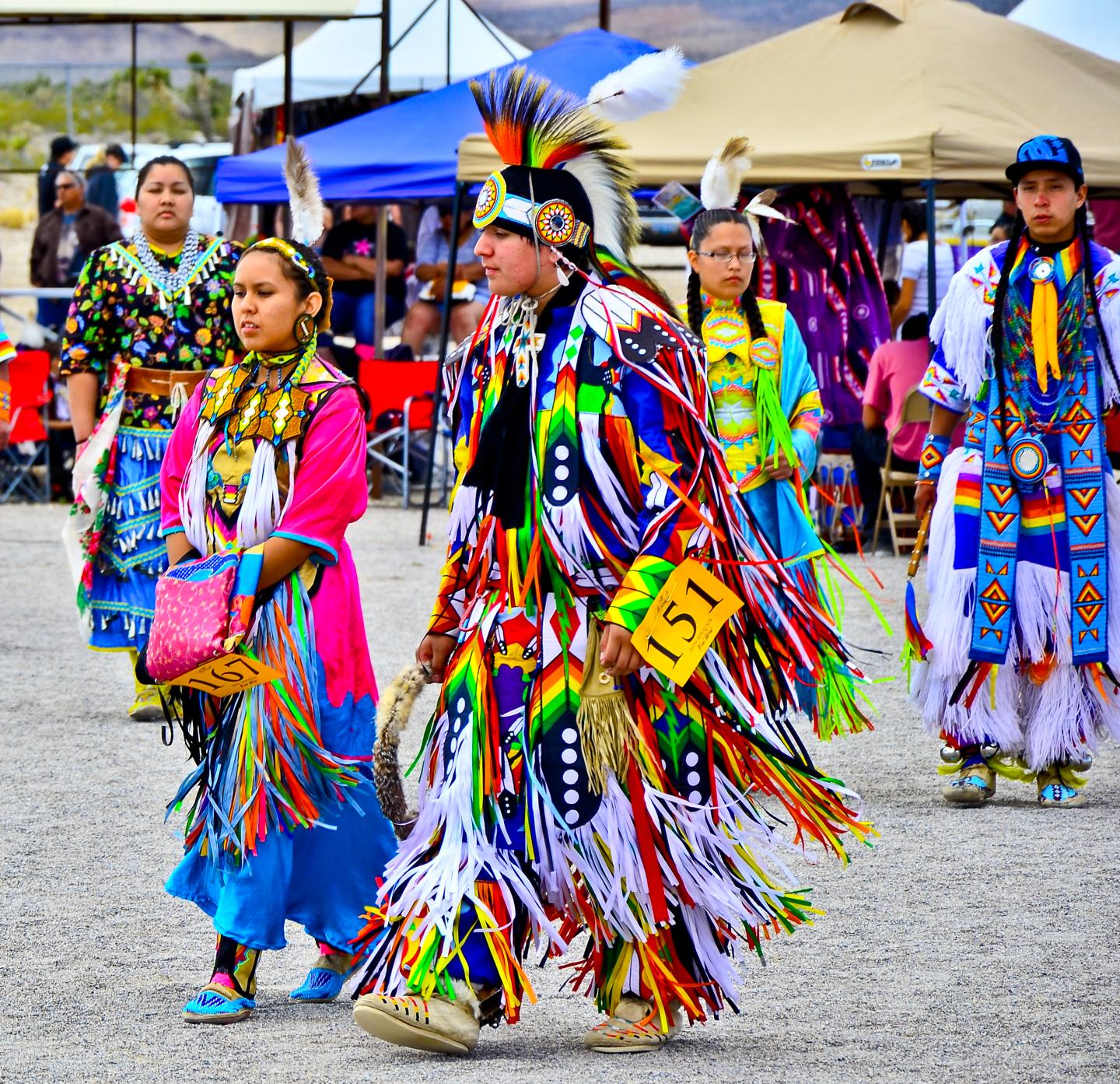 Dancers in colorful traditional attire at a lively outdoor cultural event.