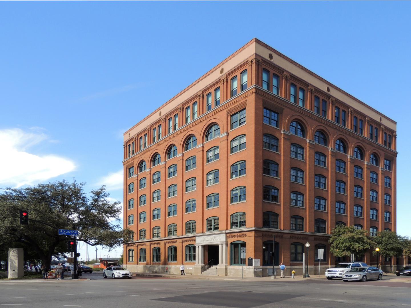 Red brick building with arched windows under a blue sky.