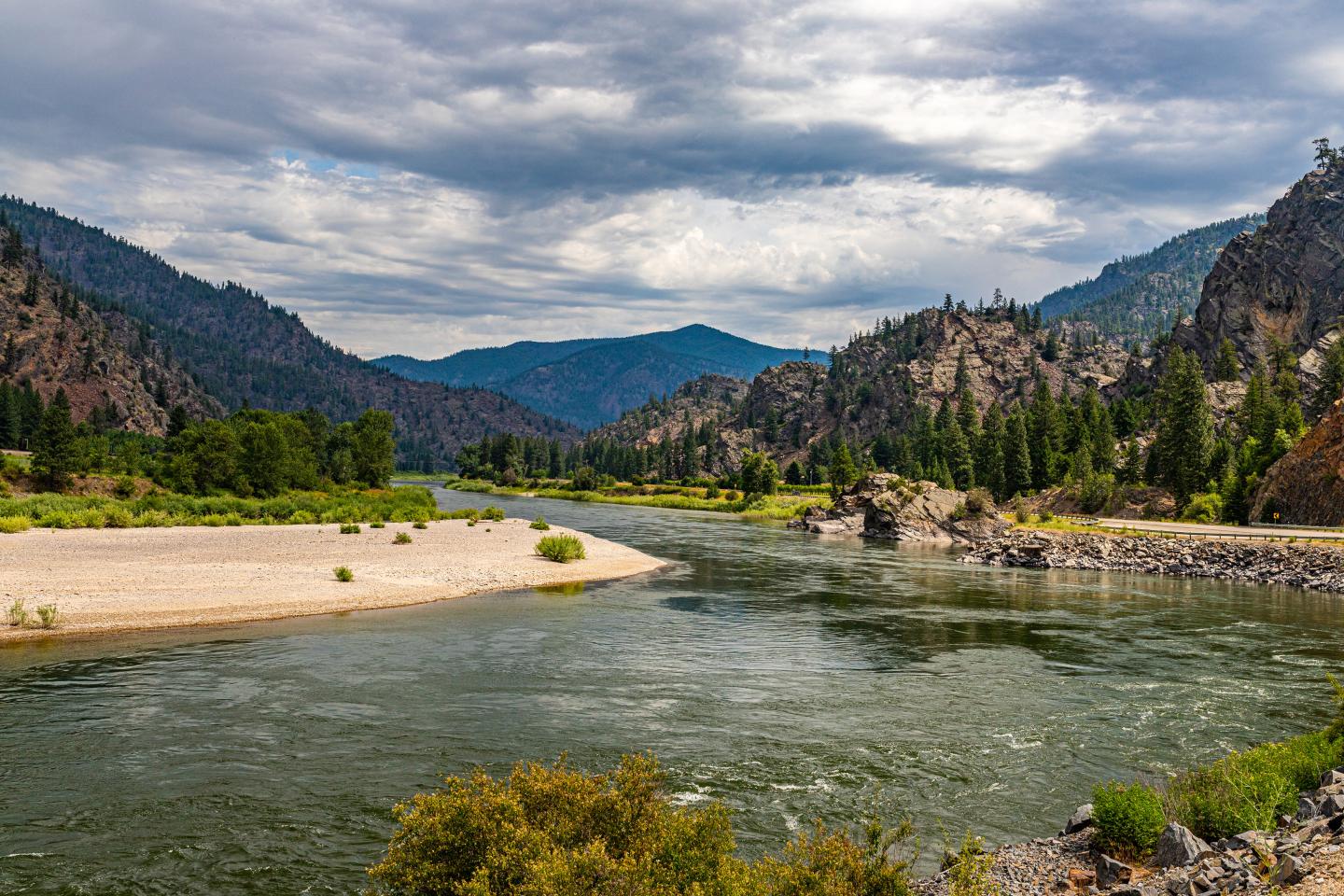 River winding through a mountainous landscape under a cloudy sky.