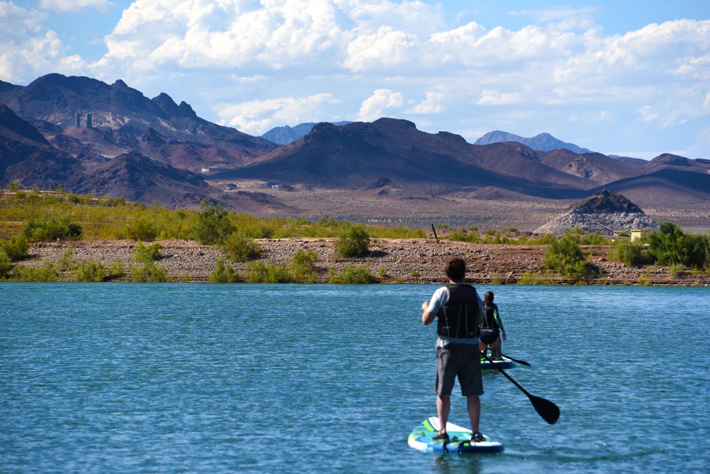 Man paddleboarding on a lake with mountains in the background.