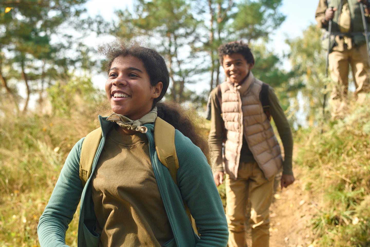 Two people hiking happily on a forest trail in autumn.