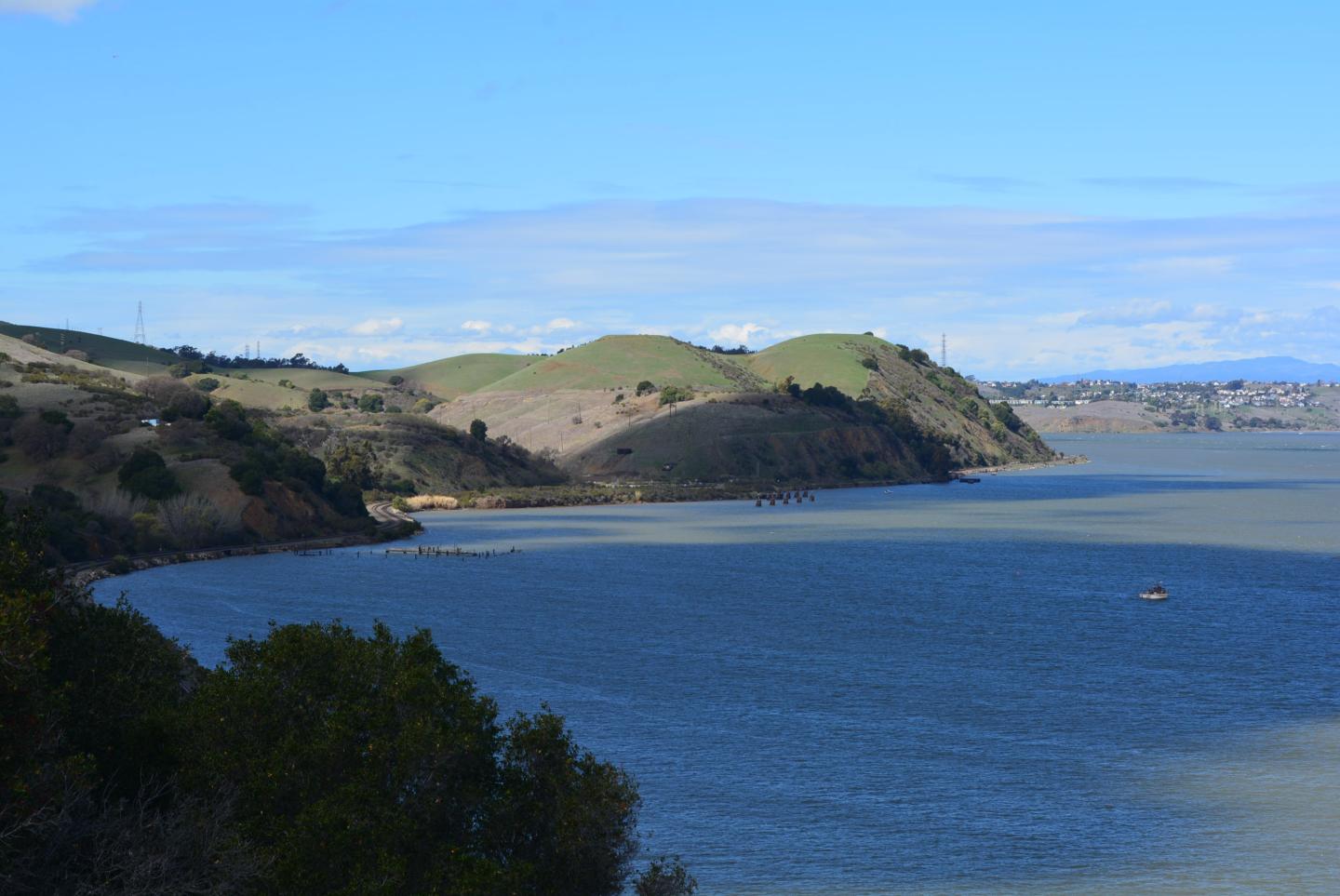 Coastline with blue water, green hills, under a clear sky.