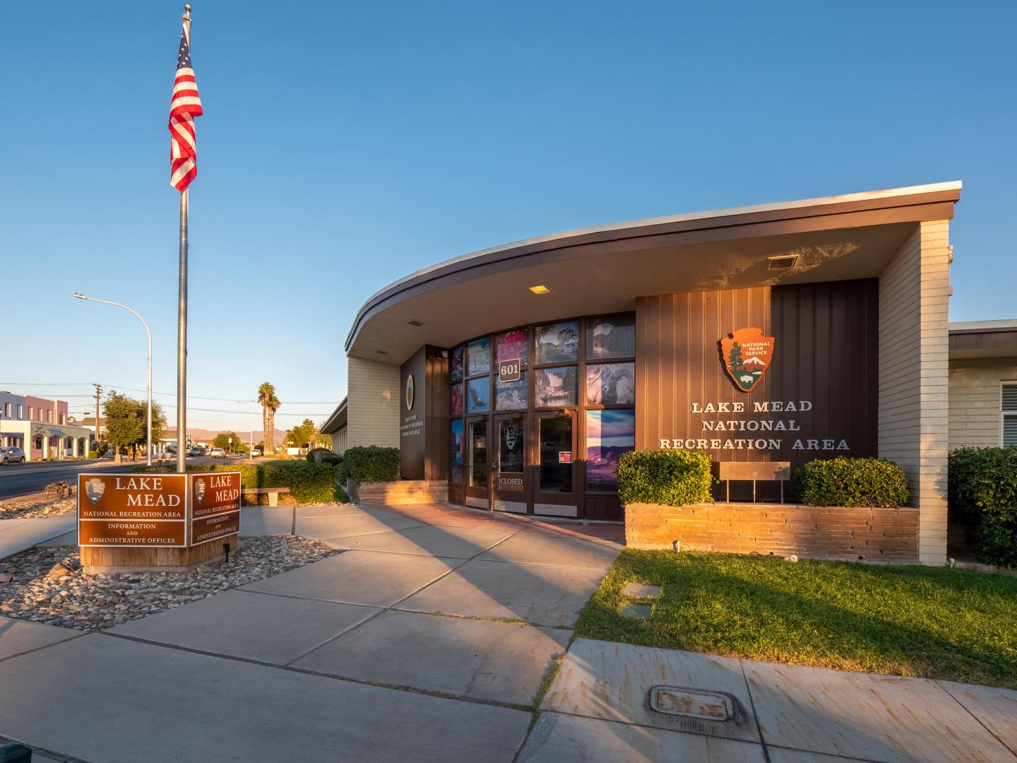 Modern visitor center with curved front and flagpole, set against a clear blue sky.