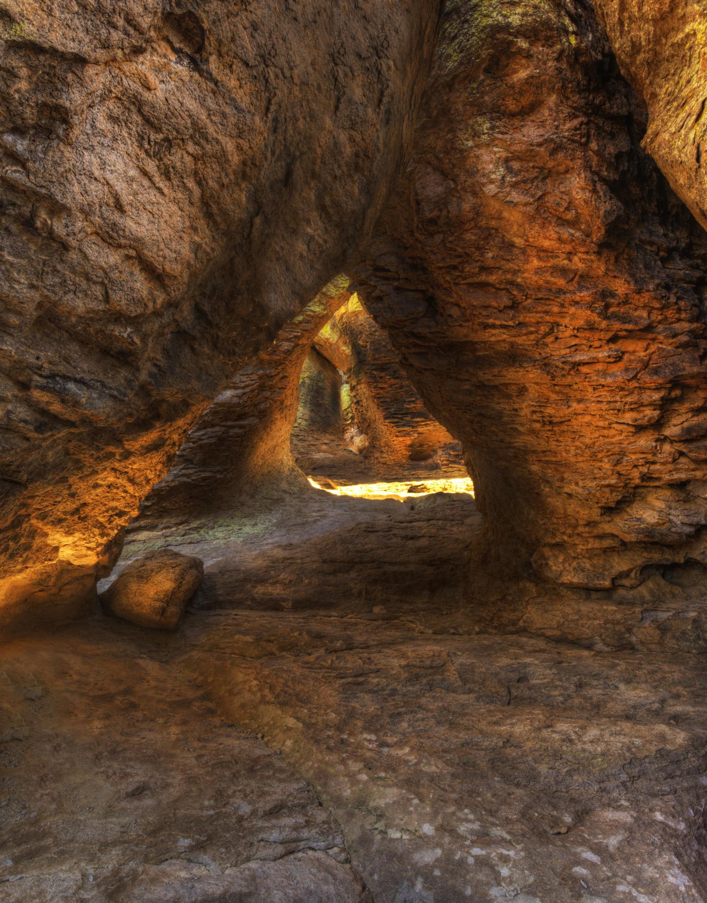 Rocky cave with warm sunlight streaming through a natural arch.