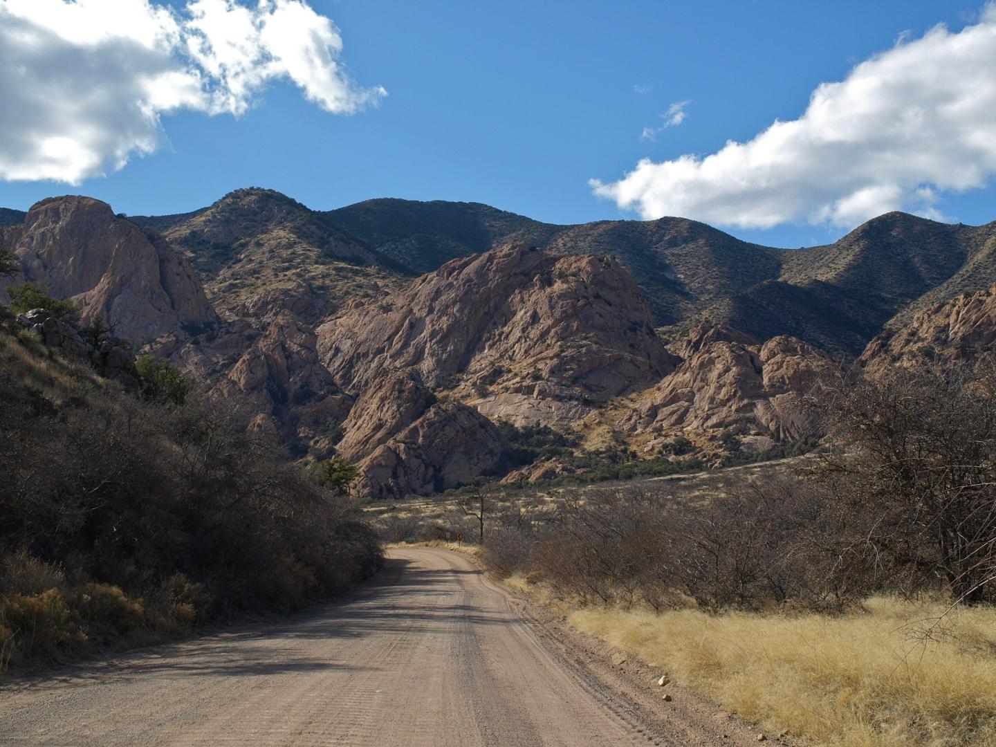 Dirt road leading to Cochise Stronghold under a blue sky with clouds.