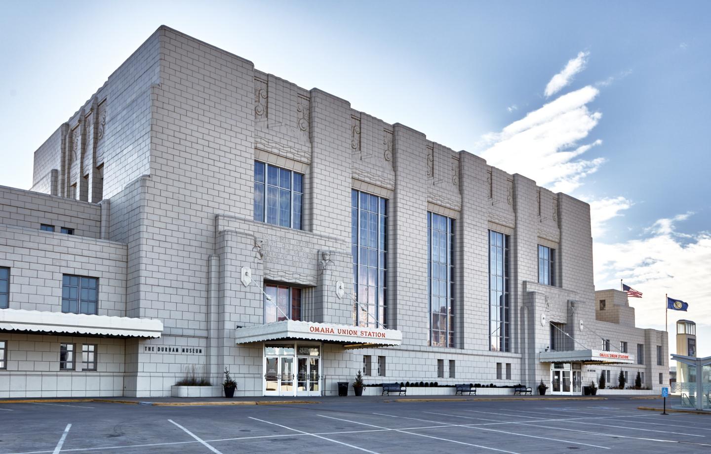 Art Deco building with large windows and cloudy sky.