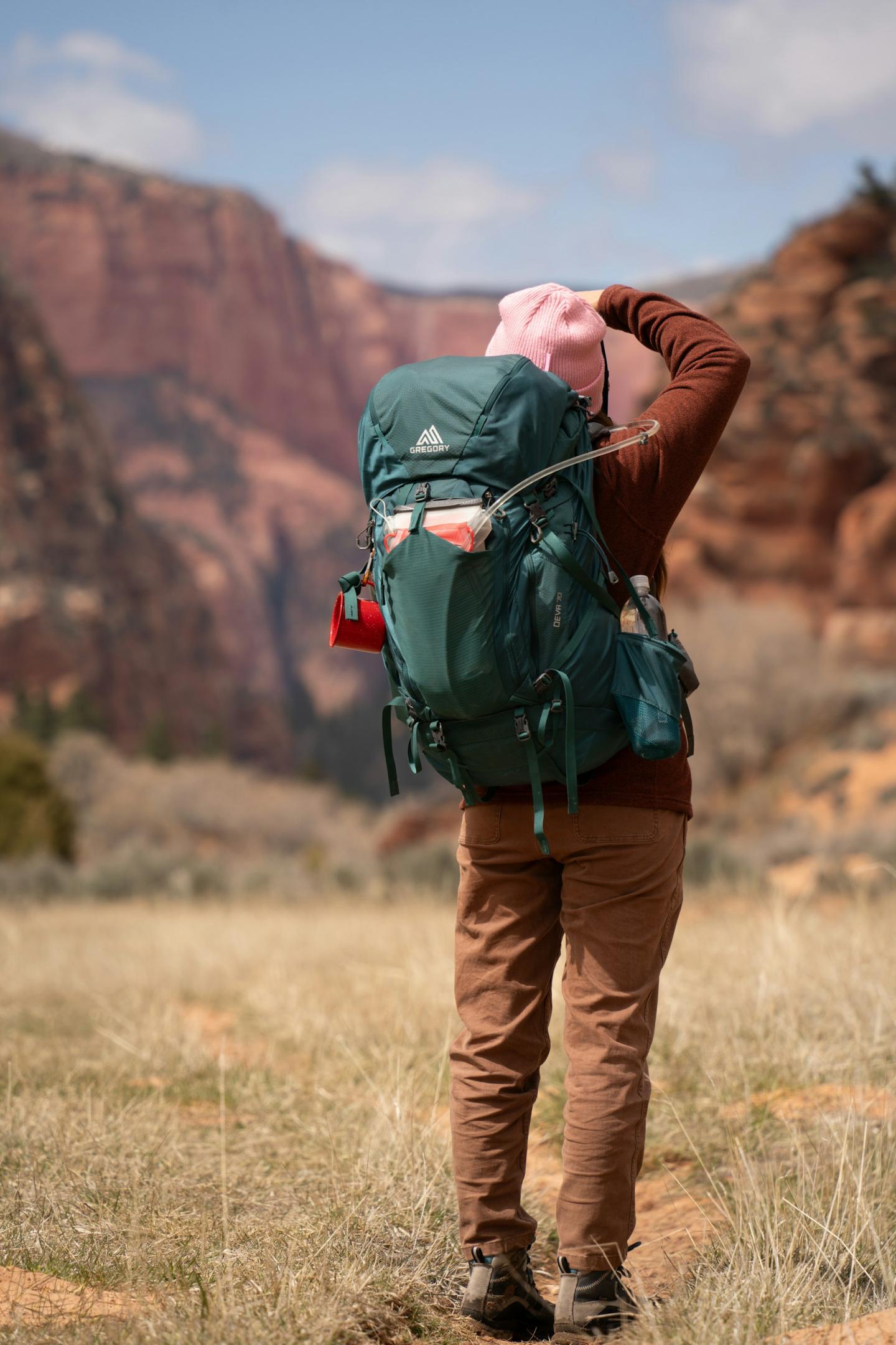 Person hiking with a large backpack in a canyon landscape.
