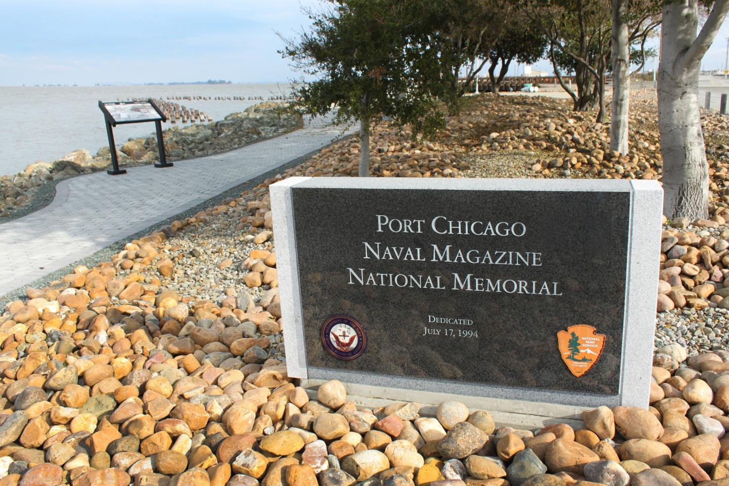 Port Chicago Naval Magazine National Memorial sign by a rocky walkway.