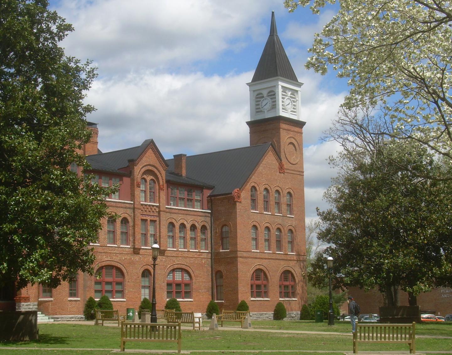 Red brick building with a clock tower under a partly cloudy sky.
