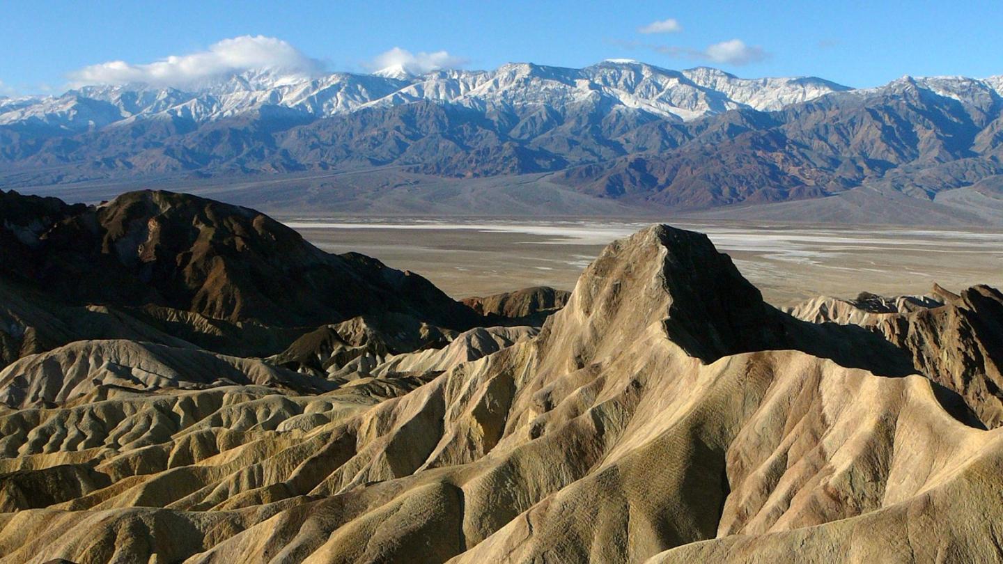 Zabriskie Point with snow-capped mountains in the background.