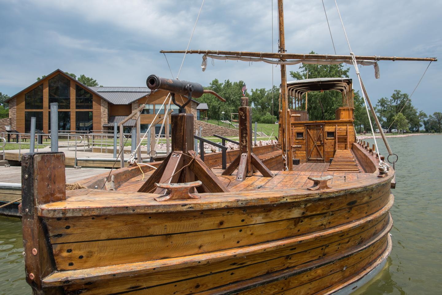 Wooden boat docked by a lake, with a cloudy sky overhead.