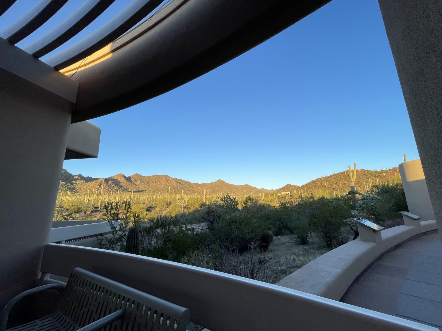 Desert landscape with mountains under a clear blue sky, viewed from a shaded patio.