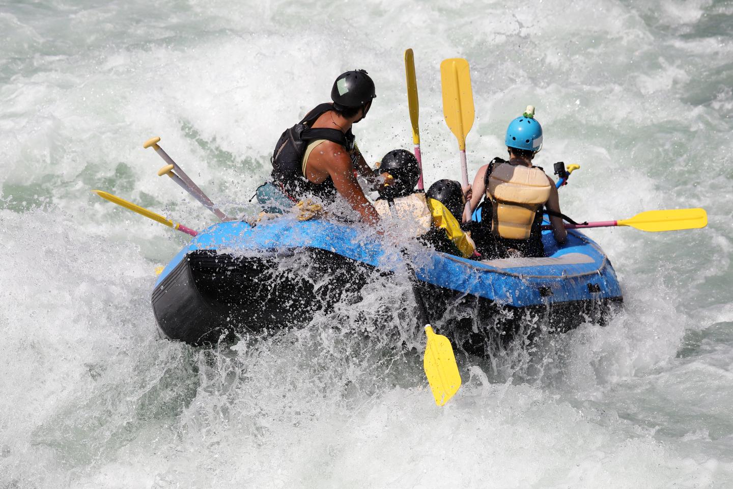 Whitewater rafters navigating a rapid in a blue inflatable raft.