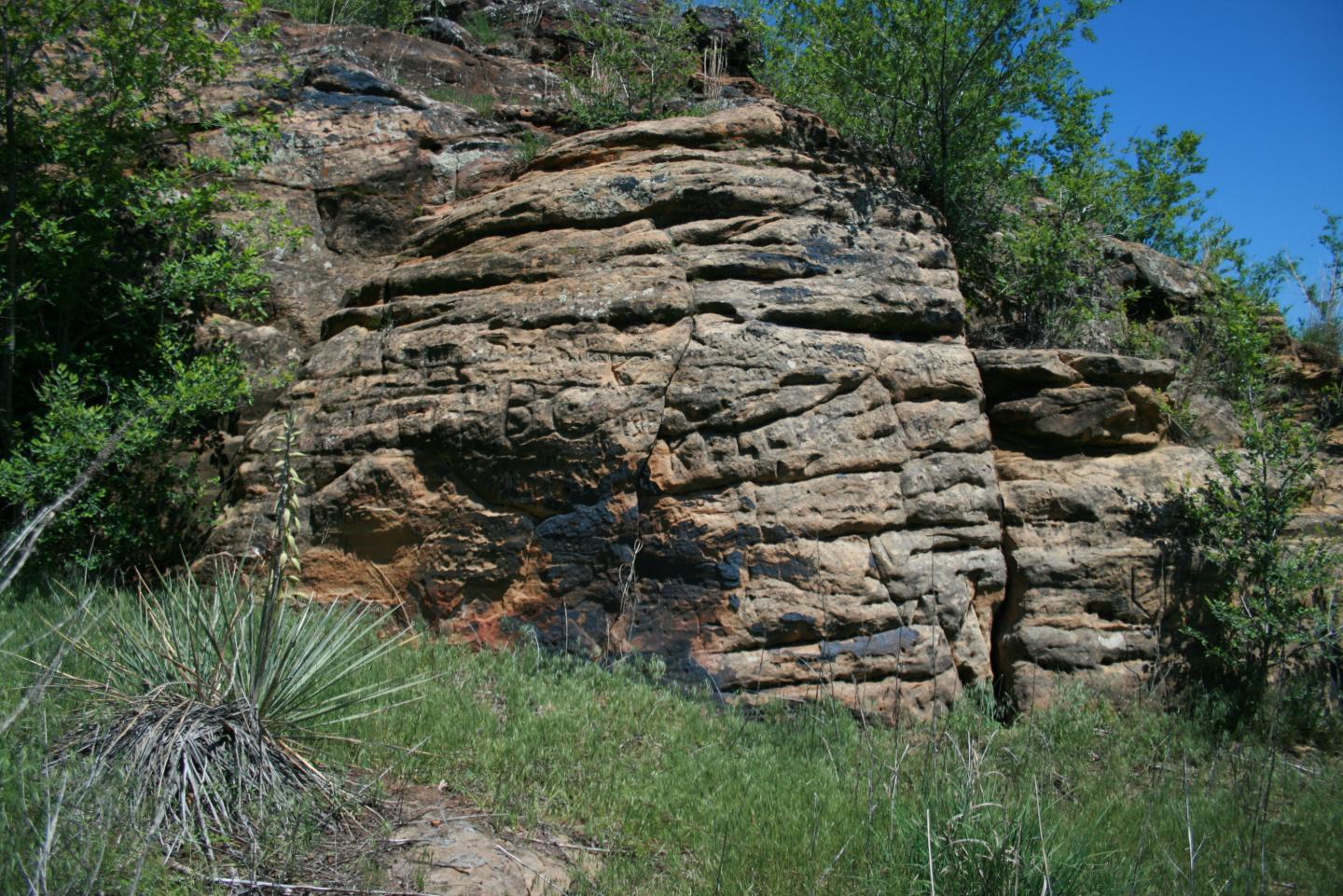 Pawnee Rock State Historic Site with green plants and clear blue sky.