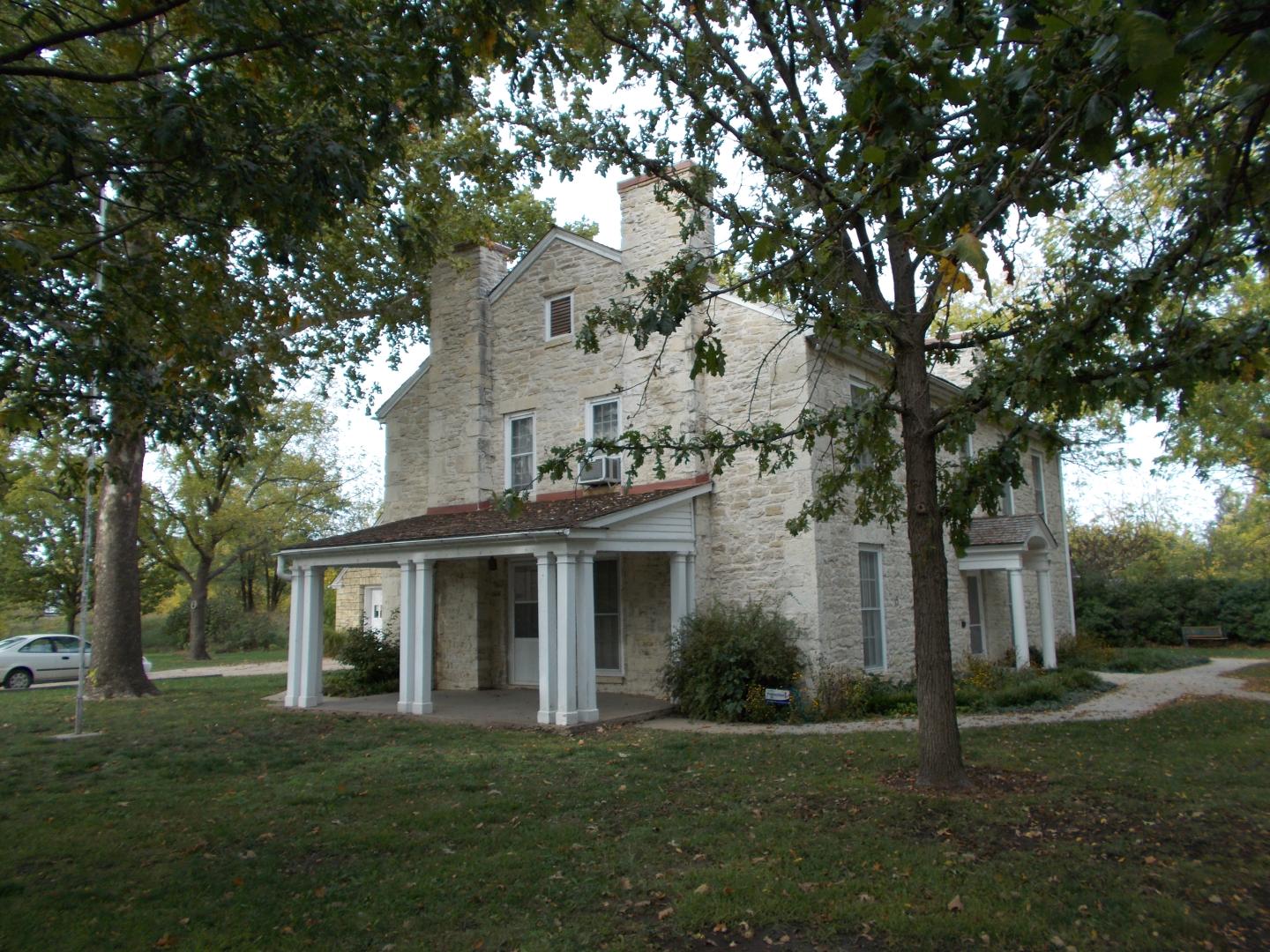Last Chance Store with columns, surrounded by trees and grassy lawn.