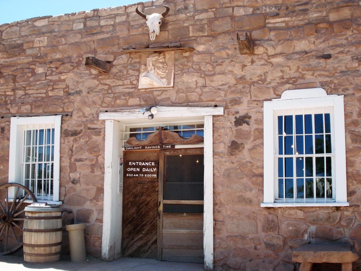 Rustic stone building facade with barred windows and a wooden door.
