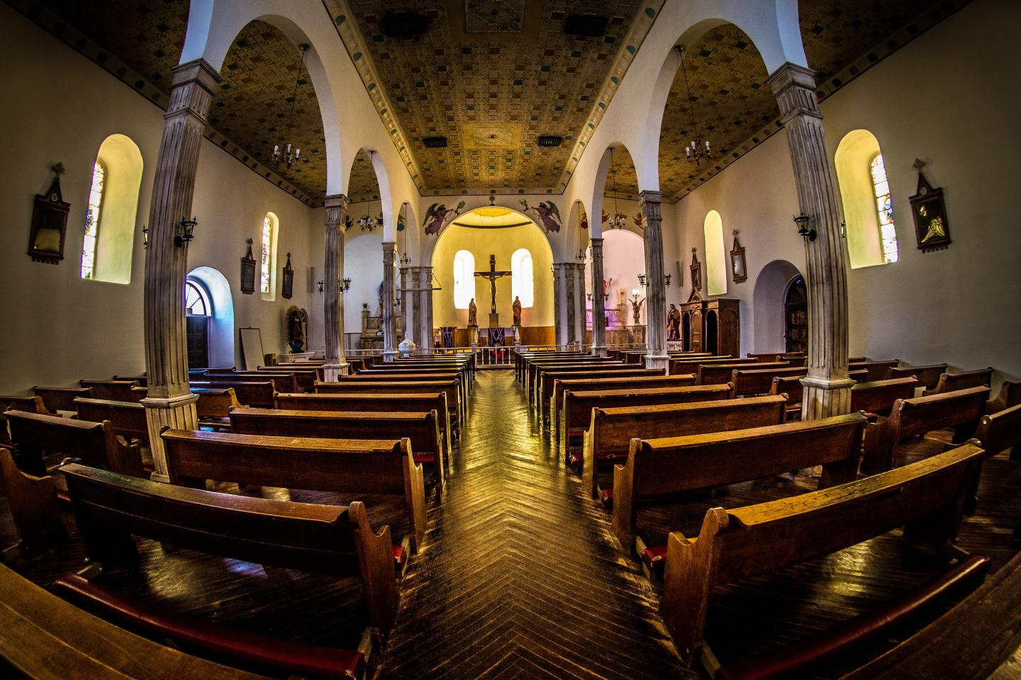 Ornate church interior with wooden pews and arched ceiling.