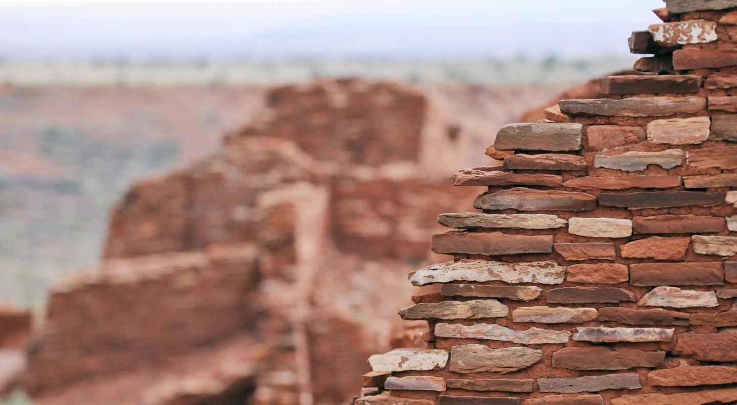 Ancient red stone wall in desert landscape, partially focused.