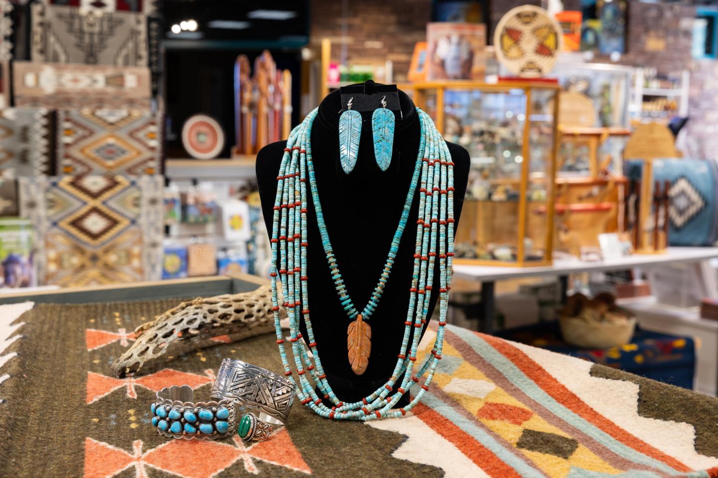 Turquoise and coral jewelry displayed on a mannequin in a colorful shop.
