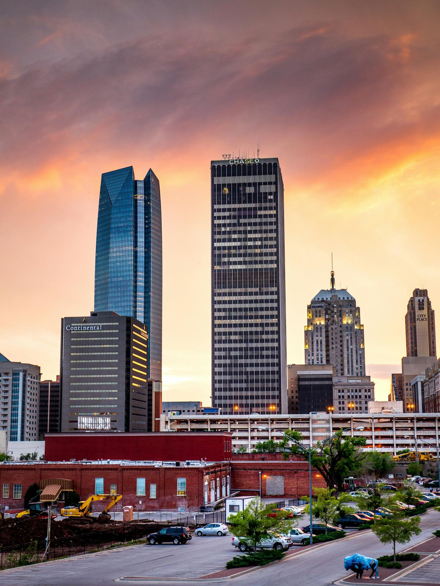 City skyline at sunset with tall buildings and a colorful sky.