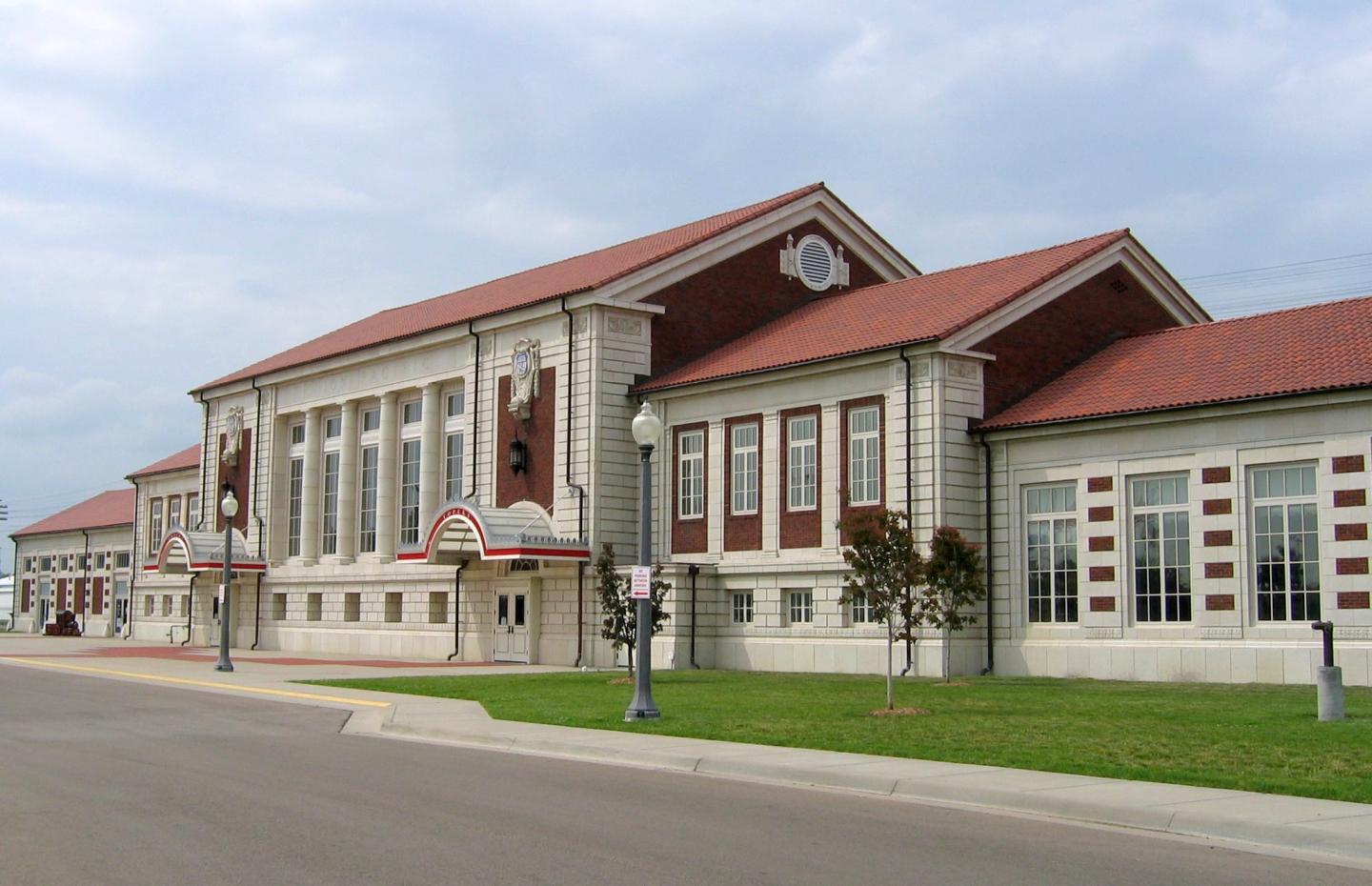 Historic building with red roof and white columns under a cloudy sky.