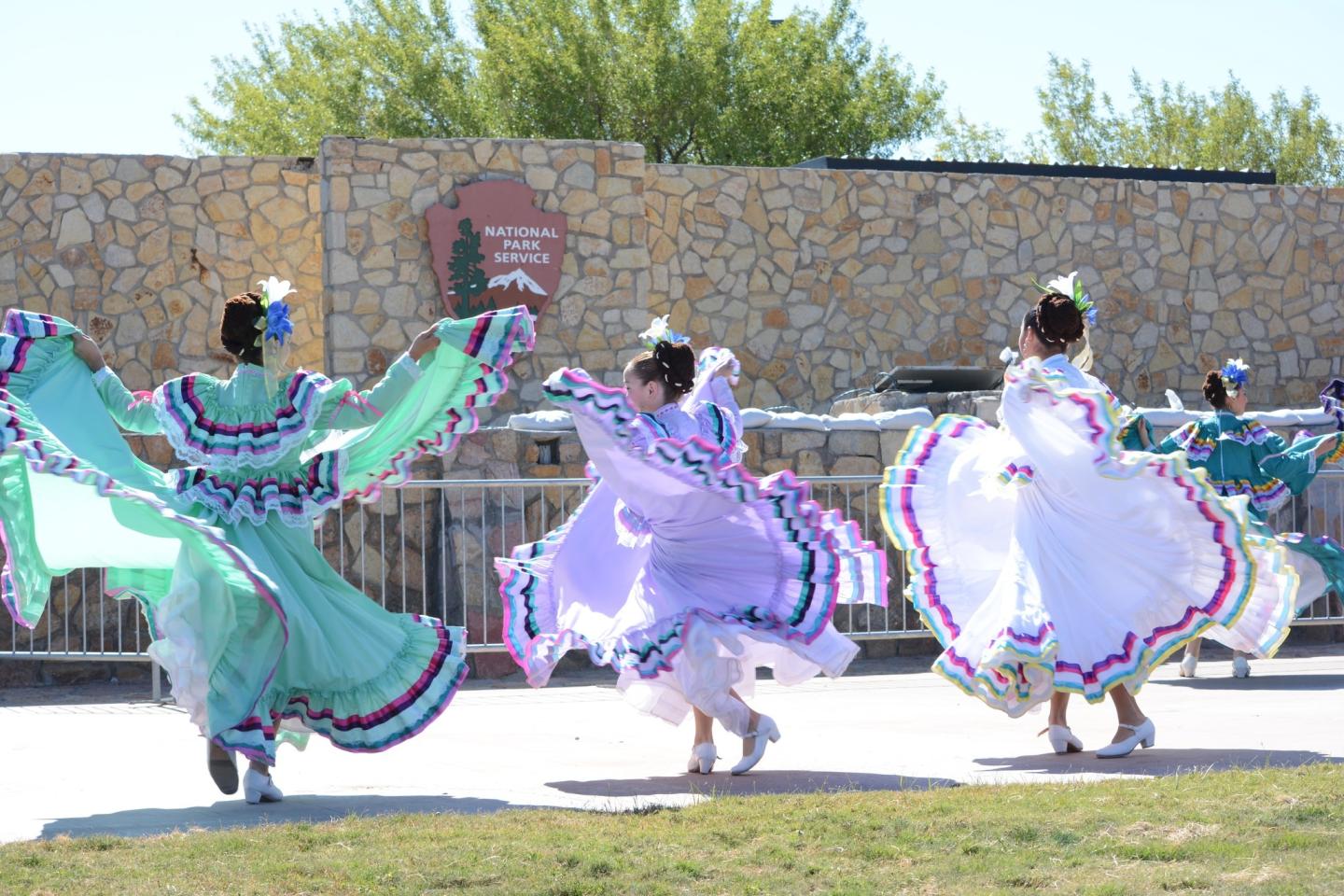 Dancers in colorful traditional dresses twirling outdoors.