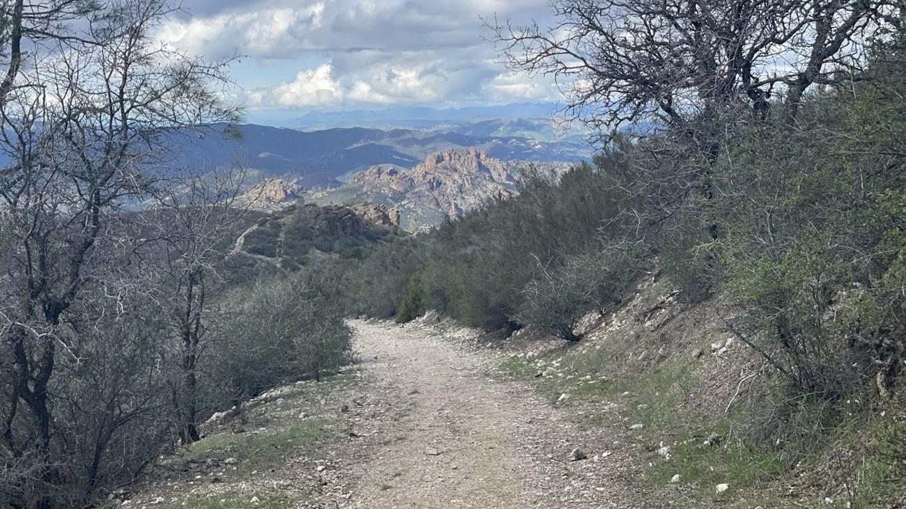 Dirt trail winding through a mountainous landscape with distant peaks.