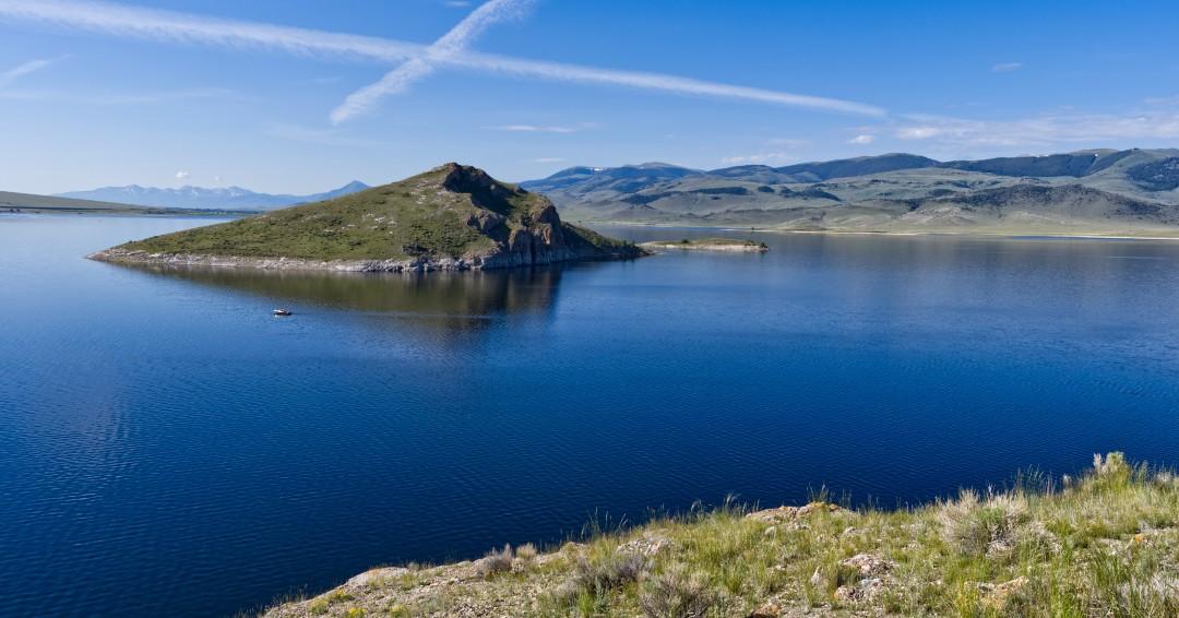 Lake with grassy island and clear blue sky.