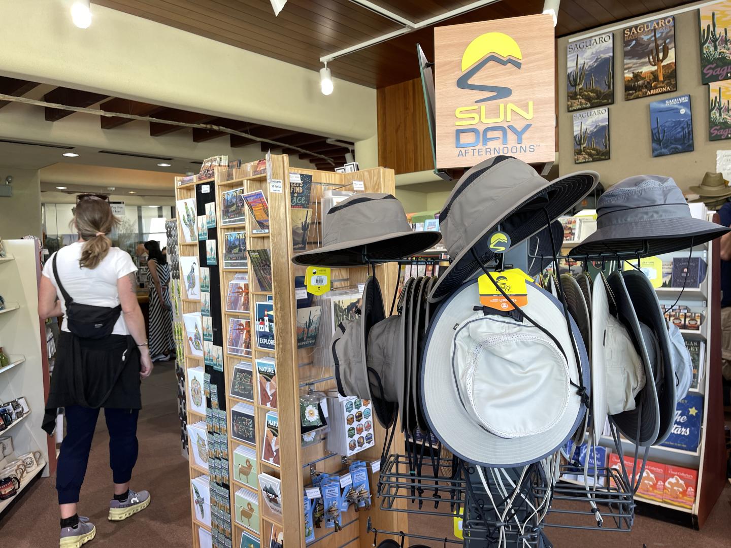 Saguaro National Park store interior with hats on display and postcards on shelves.
