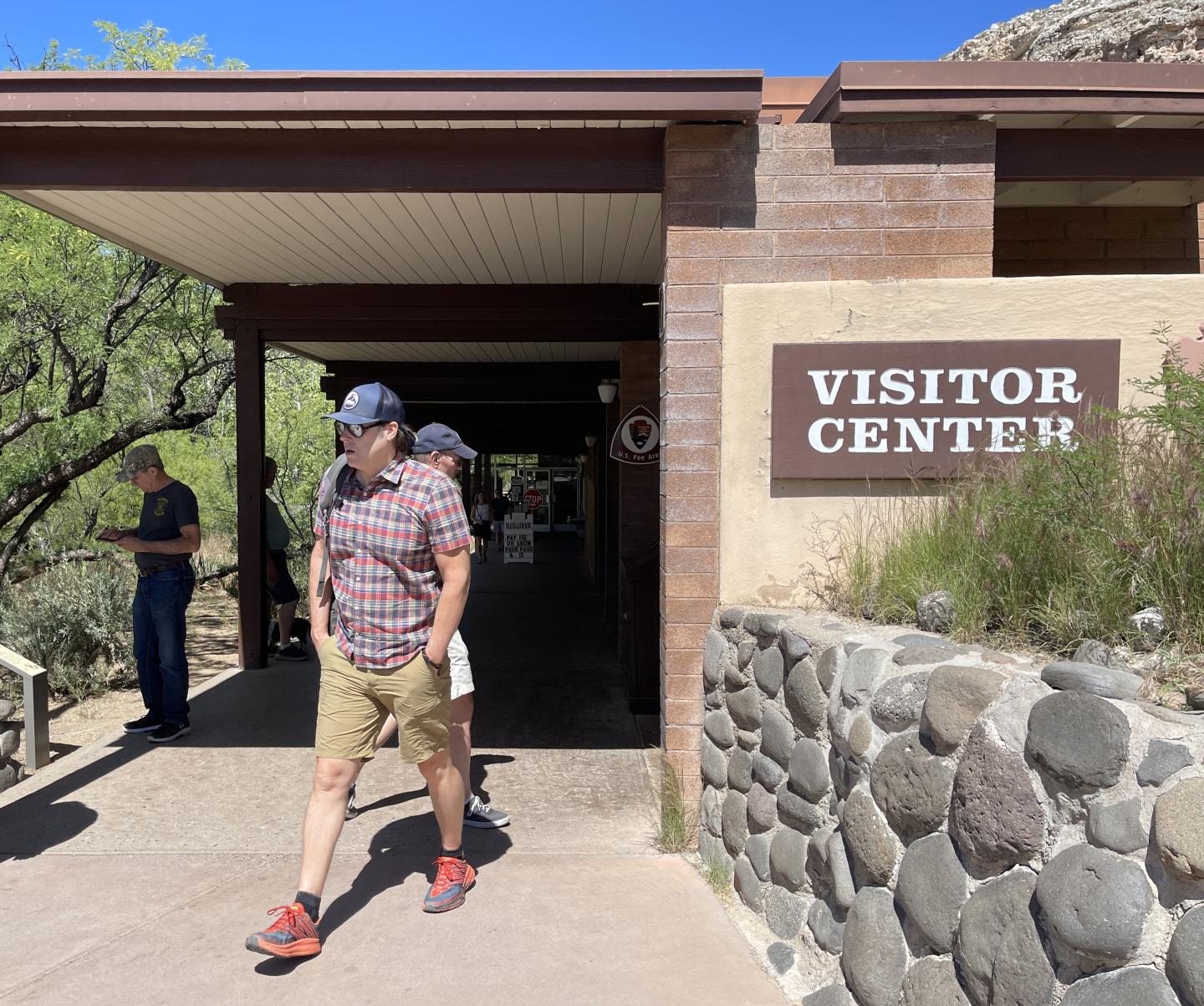 Montezuma Castle National Monument Visitor Center entrance with people walking, sunny day.
