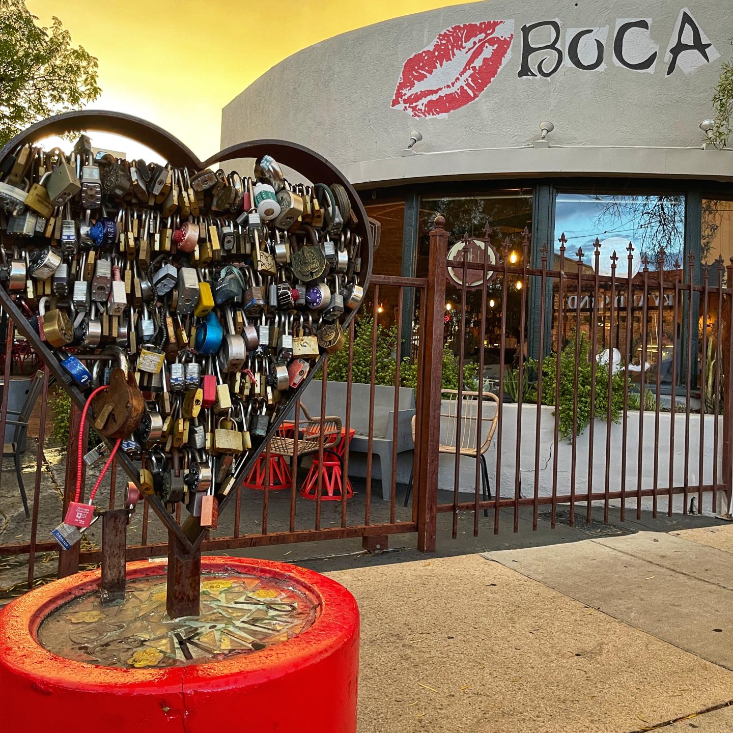 Heart-shaped lock sculpture in front of Boca restaurant with a large red kiss logo.
