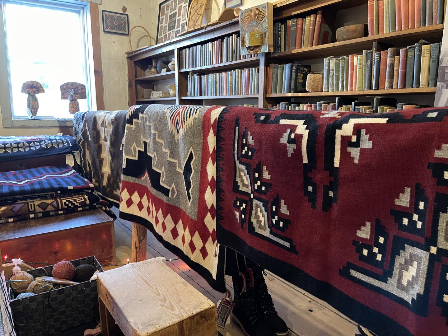 Colorful woven Navajo blankets on display in a cozy, book-filled room.