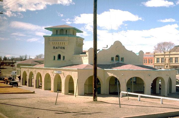Spanish-style building with arches and a tower under a blue sky.