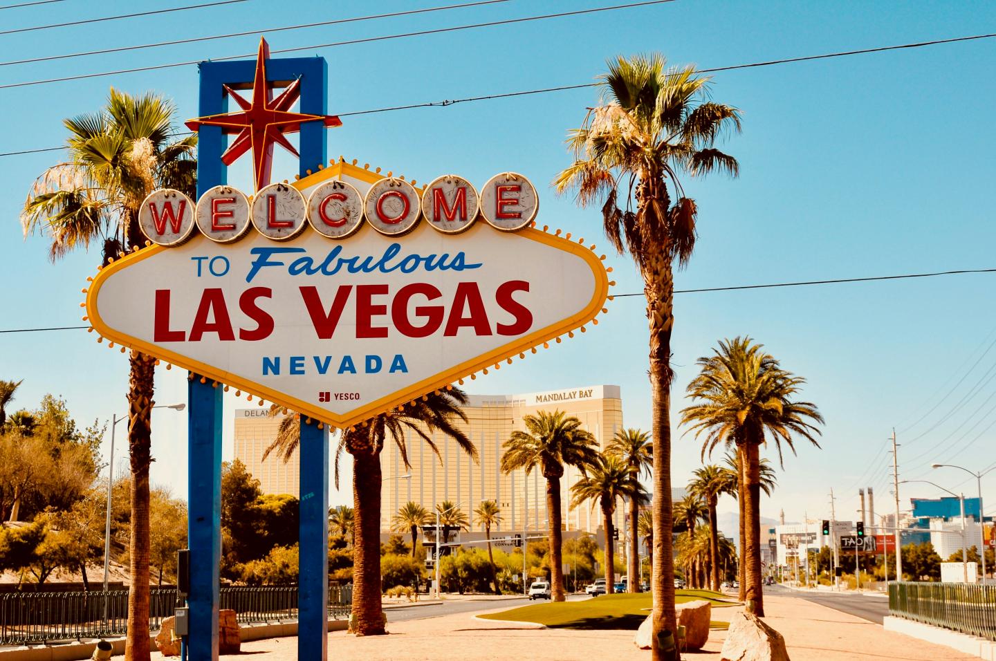Welcome to Las Vegas sign with palm trees and sunny sky.