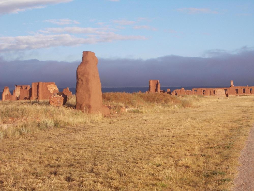 Desert landscape with ancient red stone fort union ruins under a blue sky.