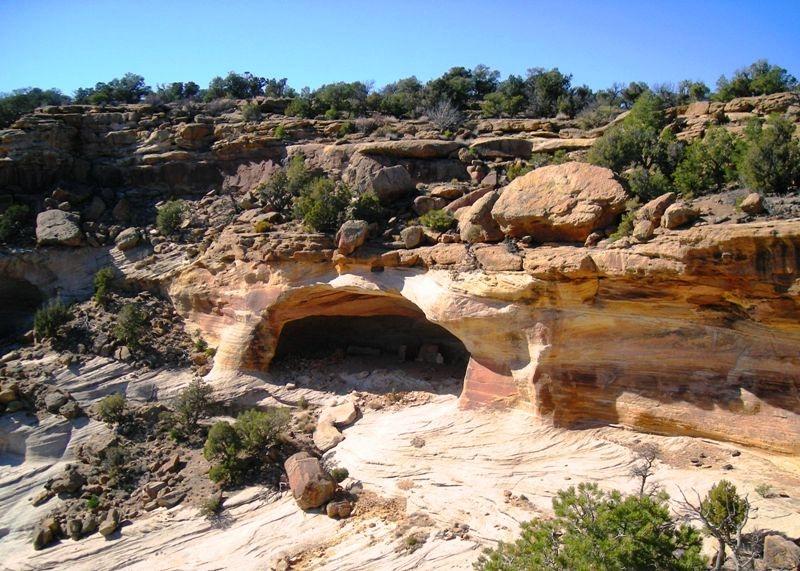 Yucca cave overlook view of natural rock arch in a desert landscape under a clear blue sky.