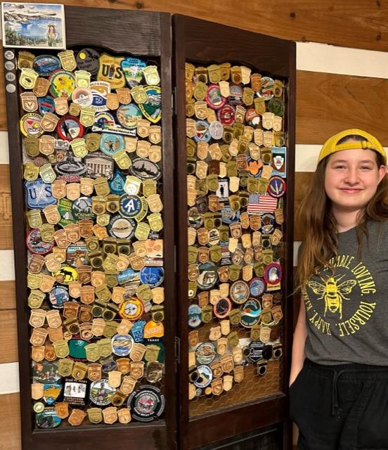 Teen beside pin/badge collection displayed on a two-panel wooden board.
