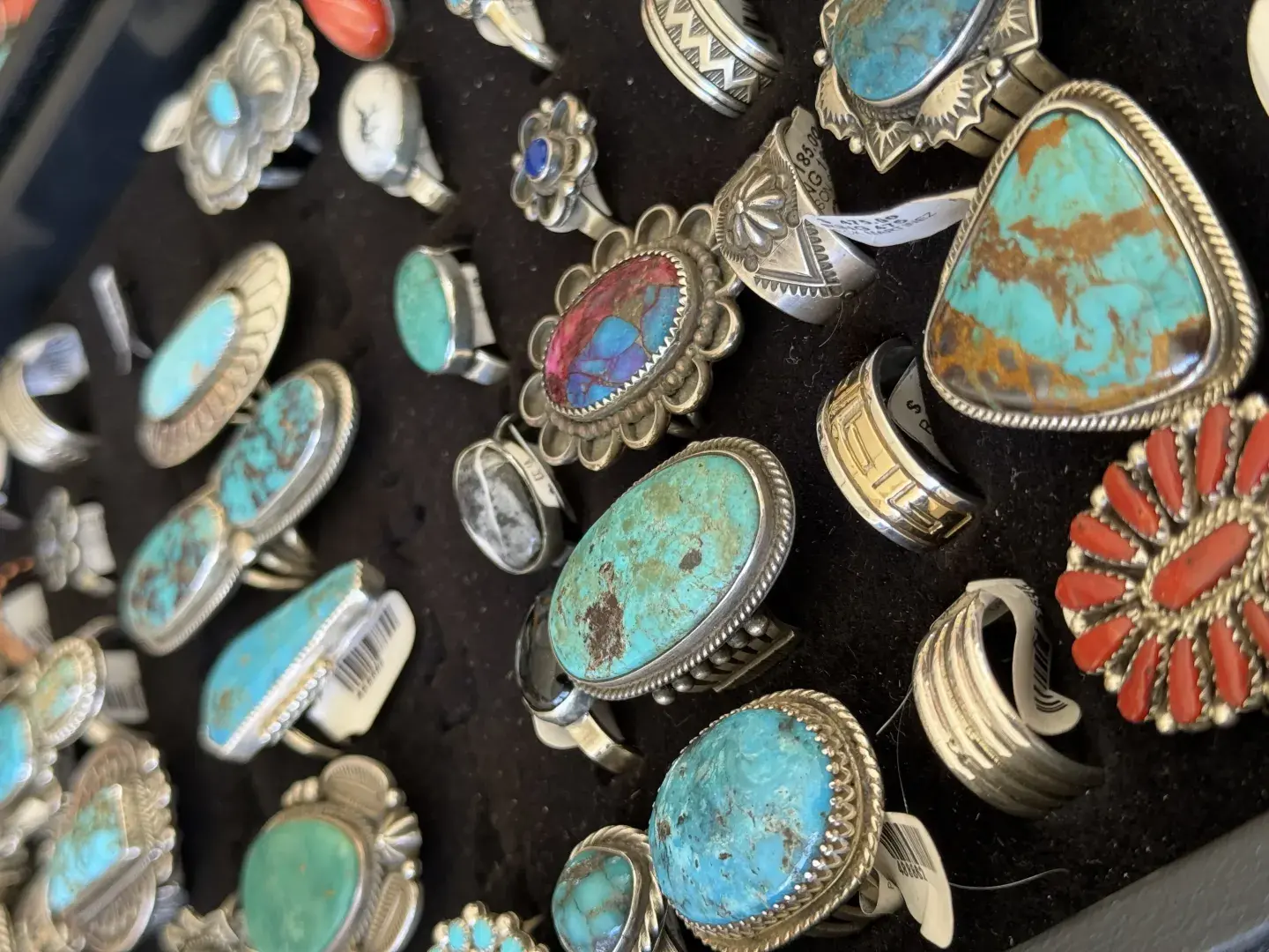 Turquoise and silver rings displayed on black fabric.