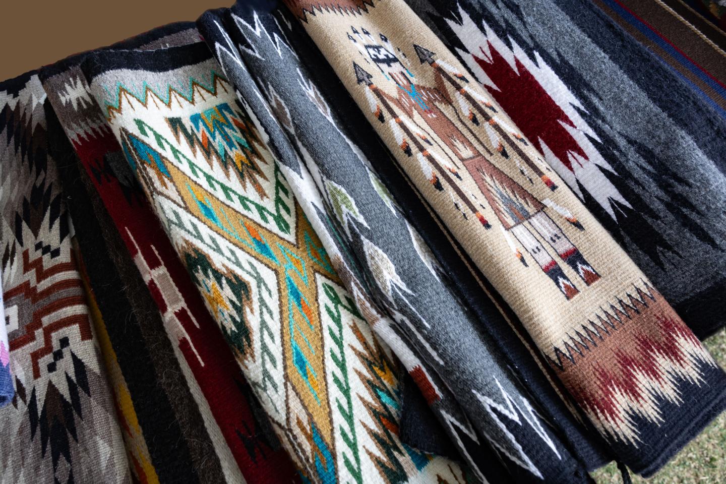 Folded woven blankets with colorful geometric patterns.