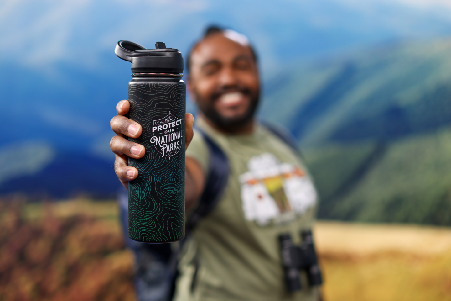 Man holding a water bottle with a mountain landscape background.