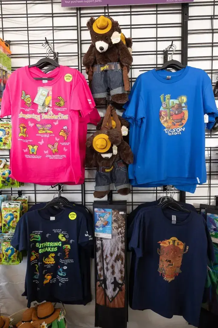 Colorful T-shirts and plush bears on display on a rack.