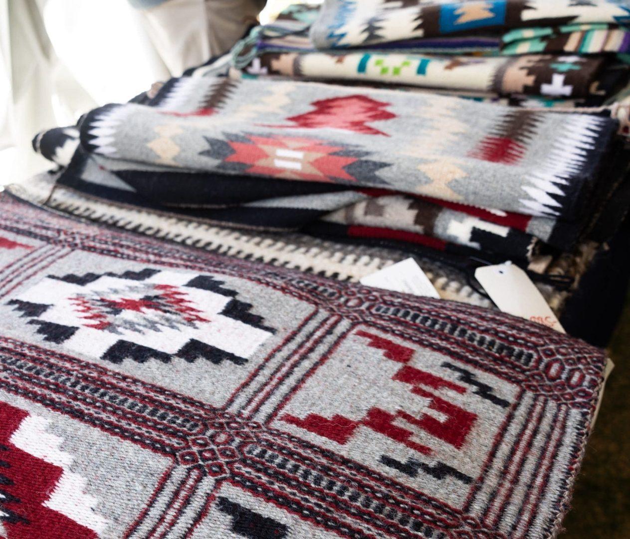 Folded woven blankets with colorful geometric patterns on display.