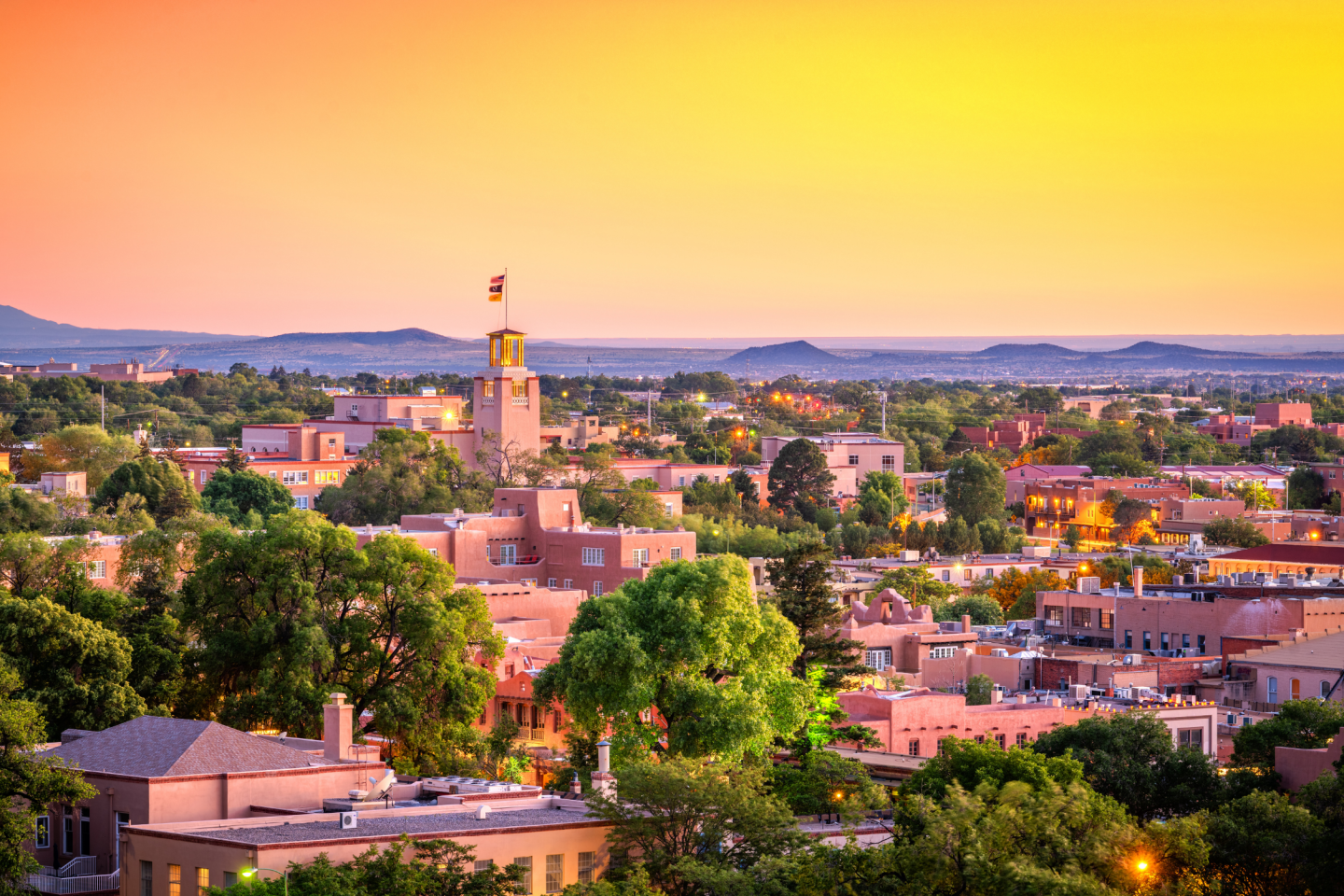 Santa Fe skyline at sunset with warm colors and distant mountains.