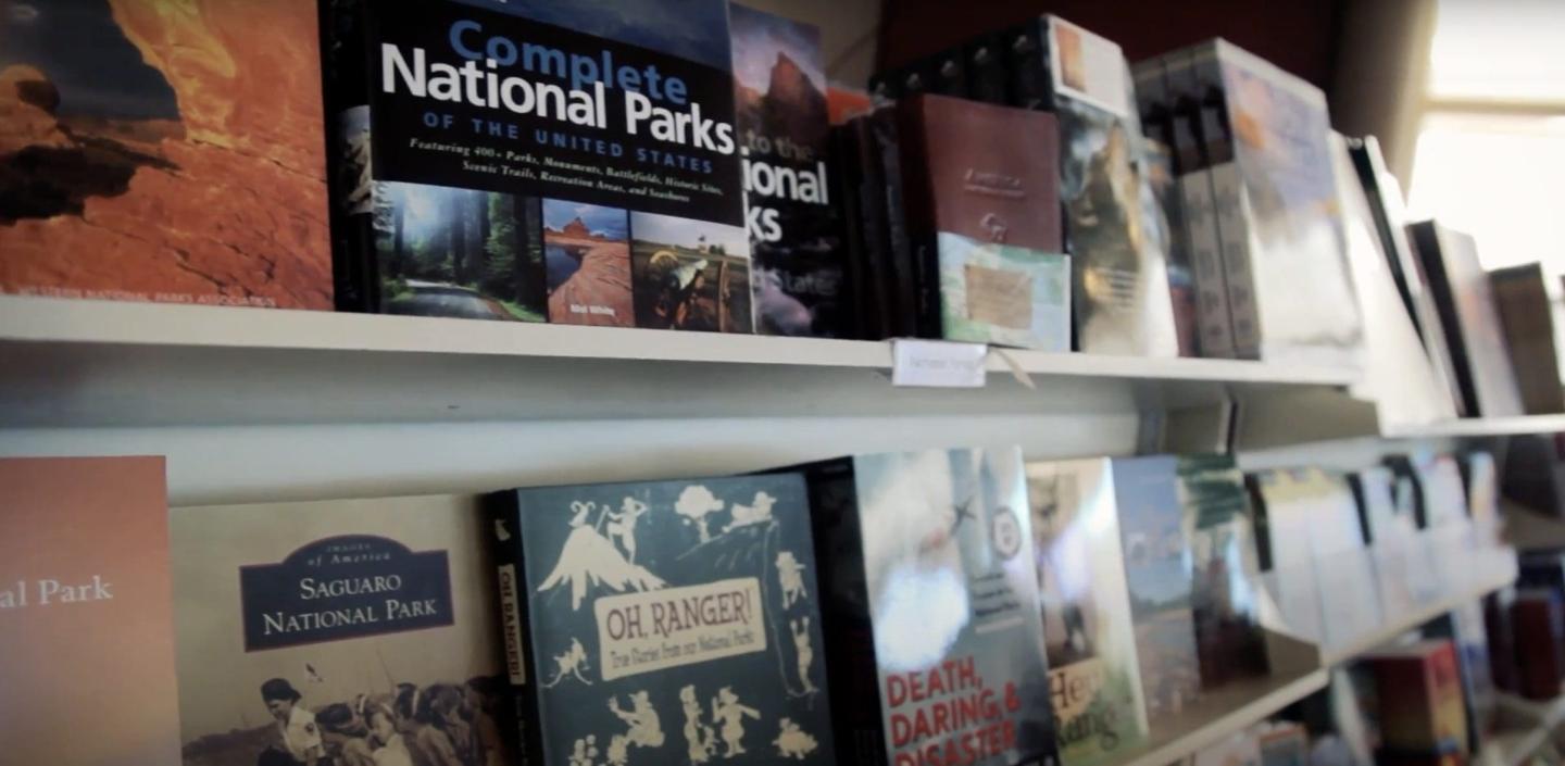 Books lined up on white shelves, featuring various national parks.